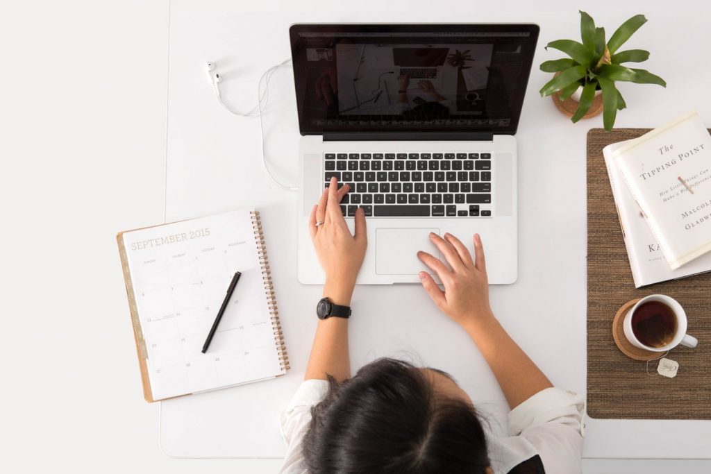 woman typing on computer coffee notebook and plant